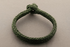 Green braided bracelet on a gray background