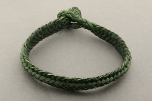 Green braided bracelet on a light gray background