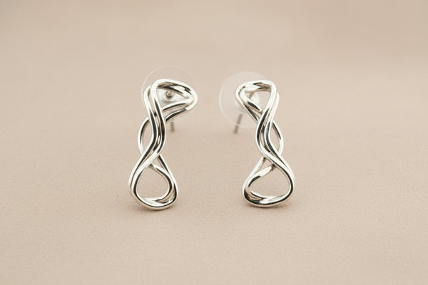 Pair of silver twisted earrings on a gray background