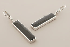 Pair of silver earrings with black stones on a gray background