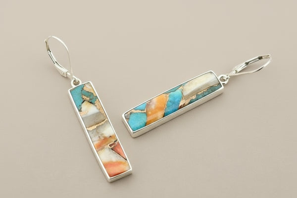 Pair of earrings with colorful stone inlay on a gray background