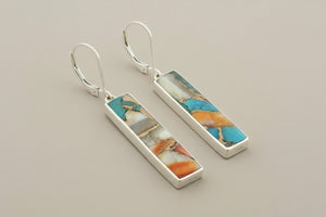 Silver earrings with colorful stone inlay on a gray background