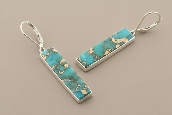 Turquoise bar earrings with gold accents on a gray background