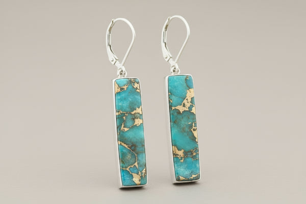 Turquoise and gold rectangular earrings on a gray background