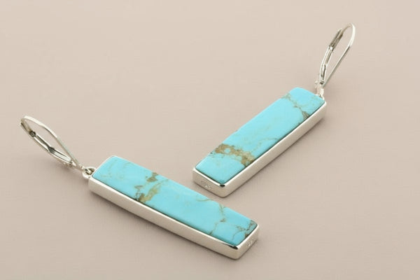 Turquoise bar earrings with silver settings on a gray background