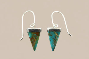 Pair of pyramid-shaped turquoise earrings on a gray background