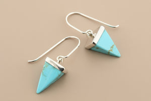 Turquoise triangle earrings on a gray background