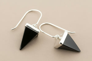 Black pyramid-shaped earrings on a gray background