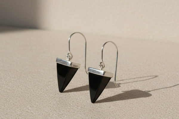 Black triangle earrings on silver hooks against a gray background