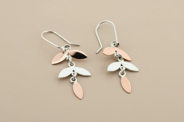 Pair of earrings with leaf-shaped charms on a dark background