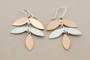Pair of earrings with leaf-shaped drops on a dark background