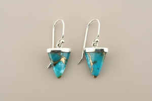 Turquoise triangle earrings with silver hooks on a gray background