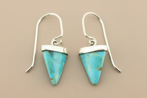 Turquoise triangle earrings with silver hooks on a gray background