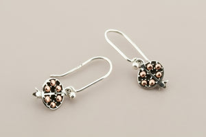 Silver earrings with rose gold accents on a gray background