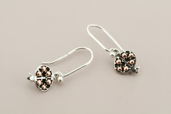 Silver earrings with rose gold accents on a gray background