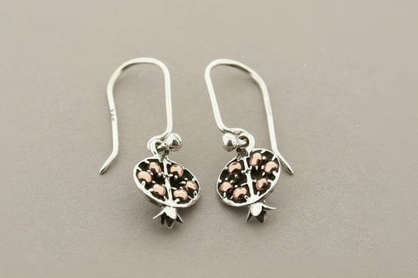 Silver earrings with intricate designs on a gray background