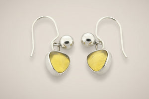 Pair of silver earrings with yellow gemstones on a gray background