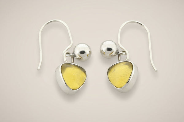 Pair of silver earrings with yellow gemstones on a gray background