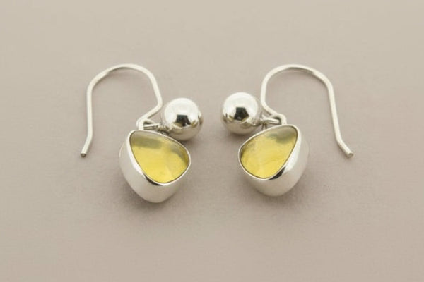 Pair of silver earrings with yellow gemstones on a dark gray background