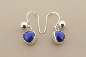 Pair of silver earrings with blue gemstones on a gray background