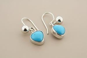 Silver earrings with turquoise stones on a gray background