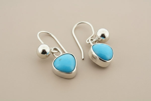 Silver earrings with turquoise stones on a gray background