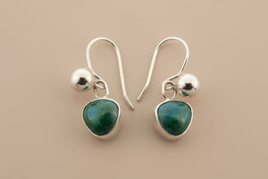 Silver earrings with green gemstones on a gray background