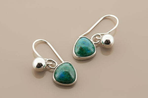 Silver earrings with green gemstones on a gray background
