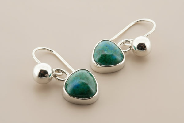 Silver earrings with green gemstones on a gray background