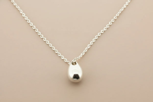Silver necklace with a small pendant on a gray background