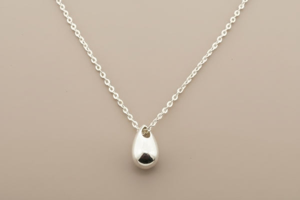 Silver teardrop pendant necklace on a gray background