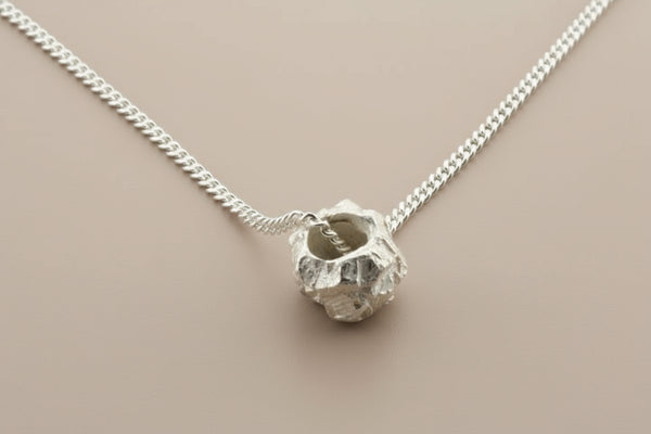 Silver necklace with a unique pendant on a gray background