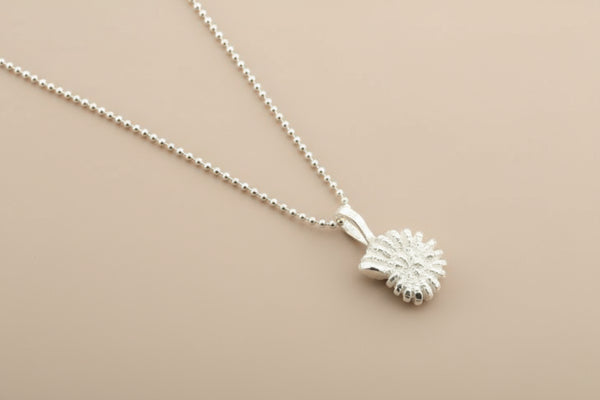 Silver necklace with a small round pendant on a gray background