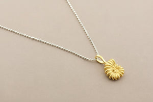 Gold shell pendant on a silver chain against a gray background