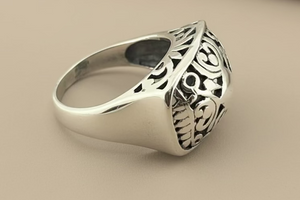 Silver ring with intricate design on a gray background
