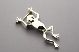 Silver frog brooch on a gray background