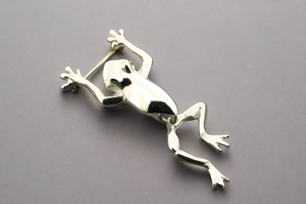 Silver frog brooch on a gray background