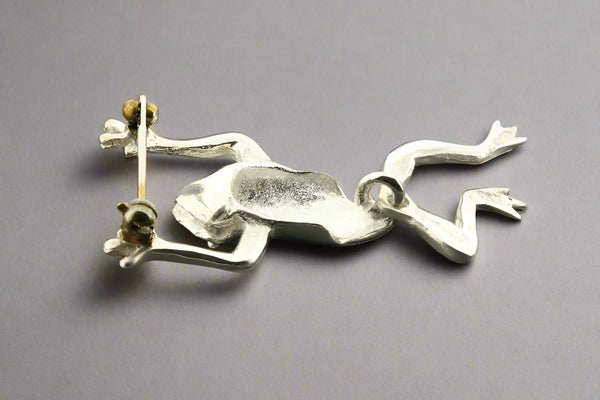 Silver frog pendant on a gray background