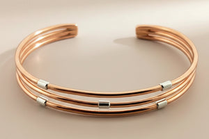 Rose gold bracelet with silver accents on a dark gray background