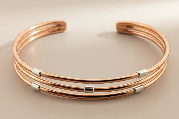 Rose gold bracelet with silver accents on a dark gray background