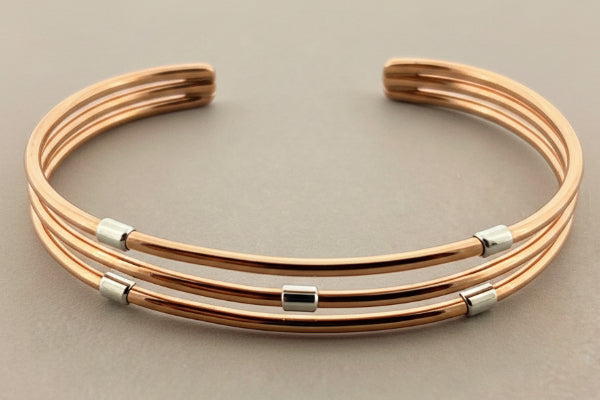 Rose gold bracelet with silver beads on a dark gray background