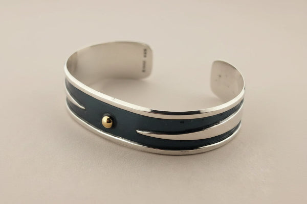 Silver bracelet with a black band on a gray background