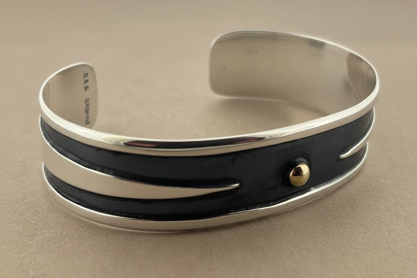 Silver and black bangle on a gray background
