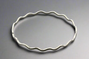 Silver bracelet with wavy design on a gray background