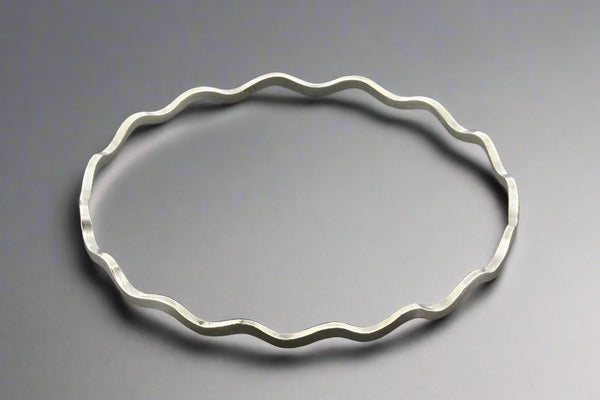 Silver bracelet with wavy design on a gray background