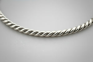 Silver twisted necklace on a gray background