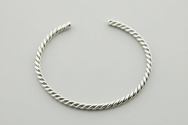 Silver twisted bangle on a gray background