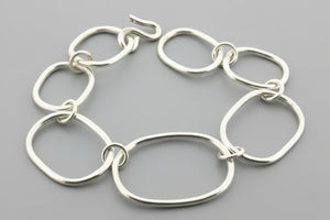 Silver bracelet with interlocking rings on a gray background