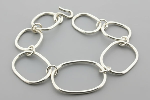 Silver bracelet with interlocking rings on a gray background