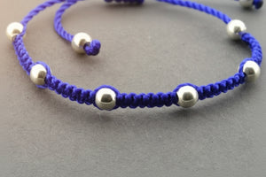 Blue macrame bracelet with silver beads on a gray background